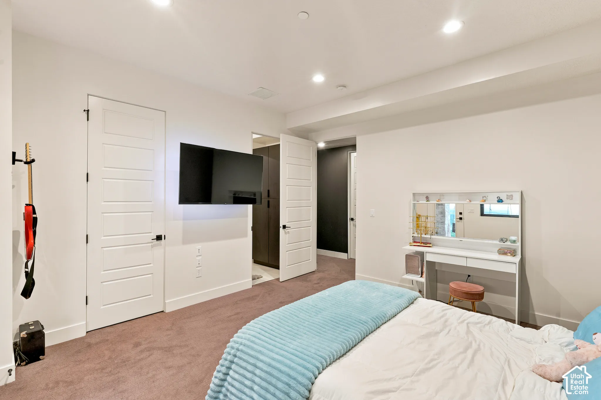 Recessed lighting illuminates the space, featuring white paneled doors with matte black hardware and wall-to-wall carpeting