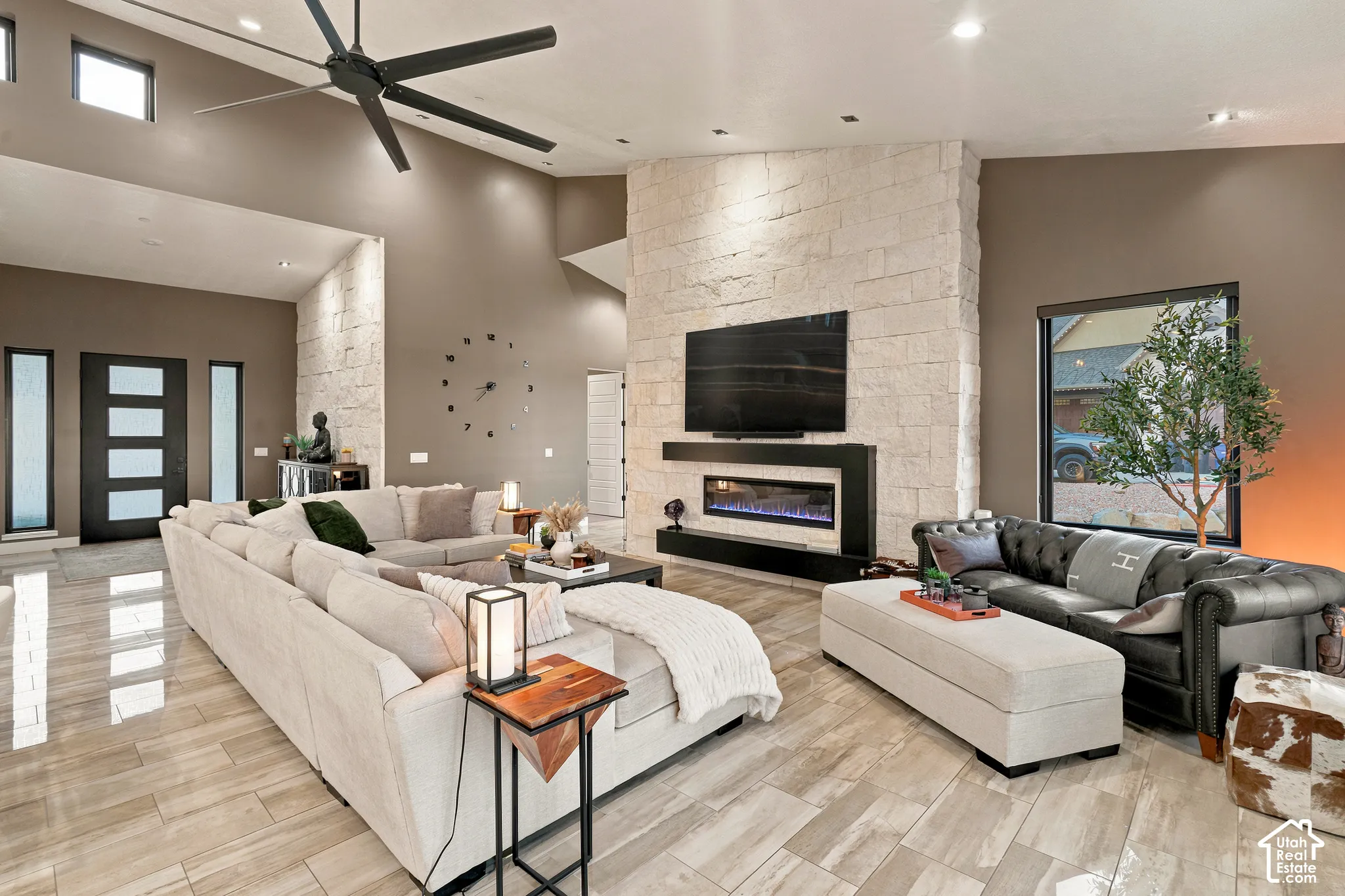 Vaulted ceiling, stone accent wall, recessed lighting, wood-finish flooring, and a modern fireplace