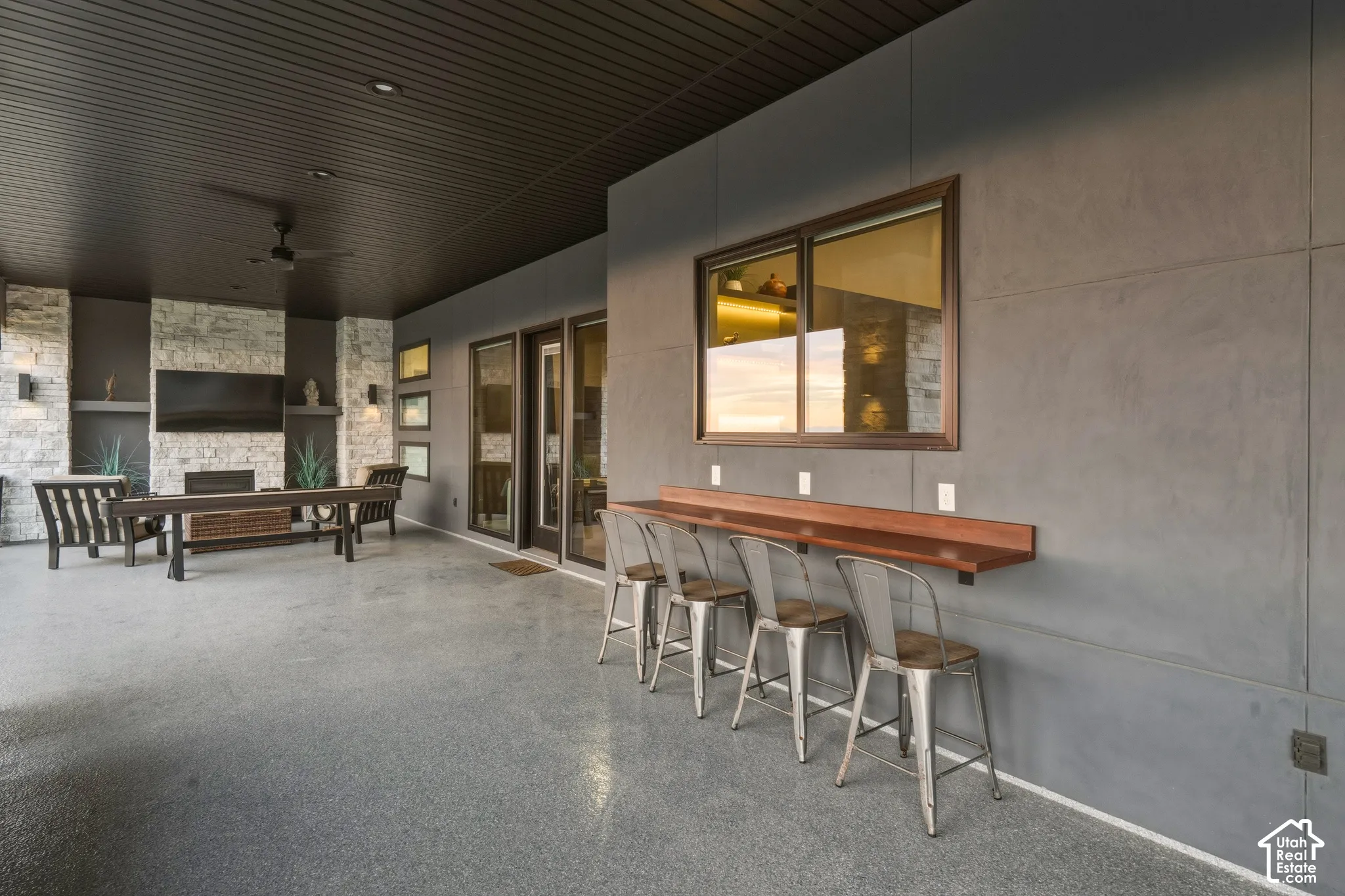 Covered patio featuring a stone-clad fireplace and built-in shelving