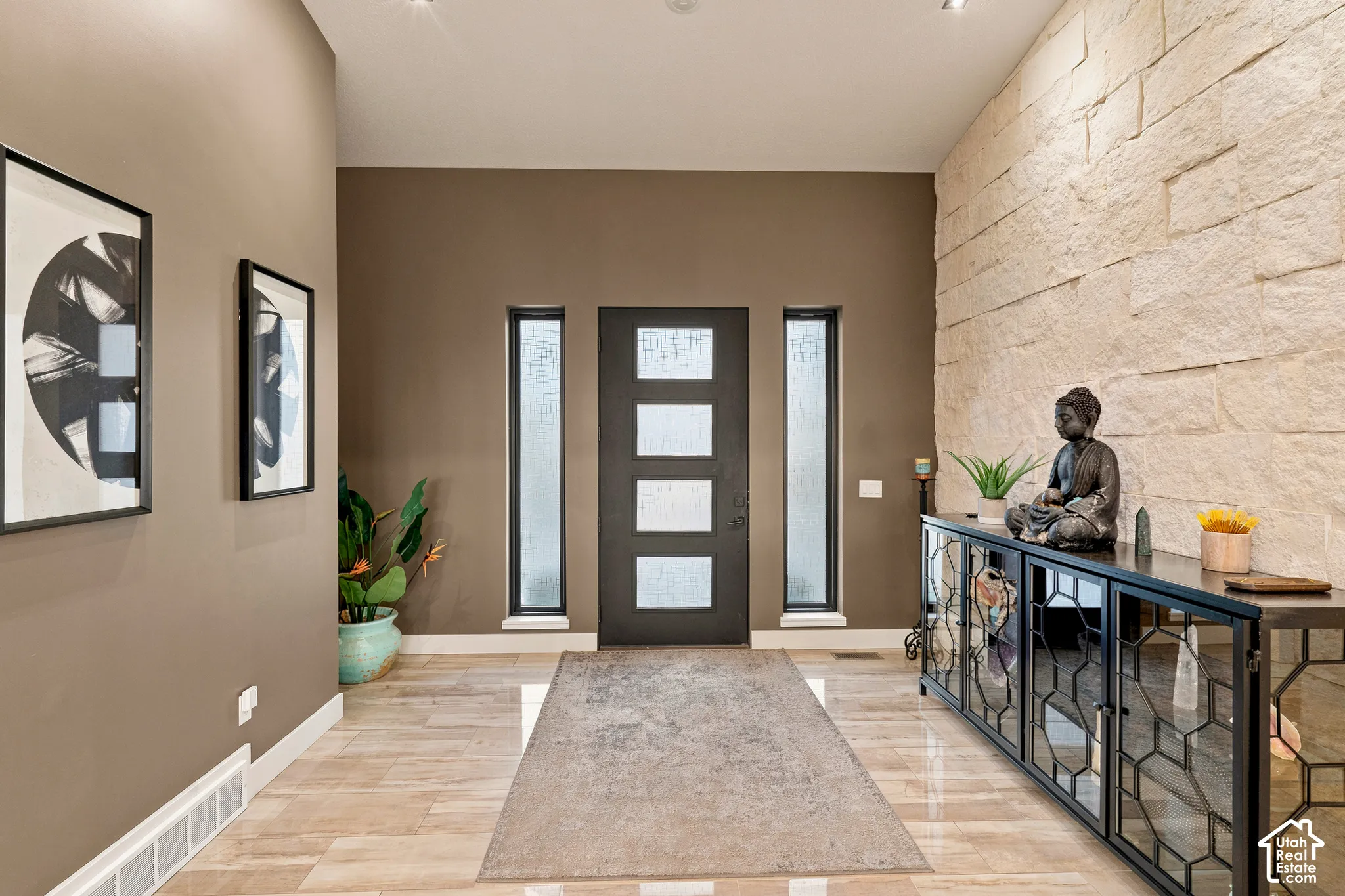 Welcoming foyer featuring a dark-stained entry door with frosted glass panels flanked by sidelights, warm taupe walls, and wood-finish plank flooring