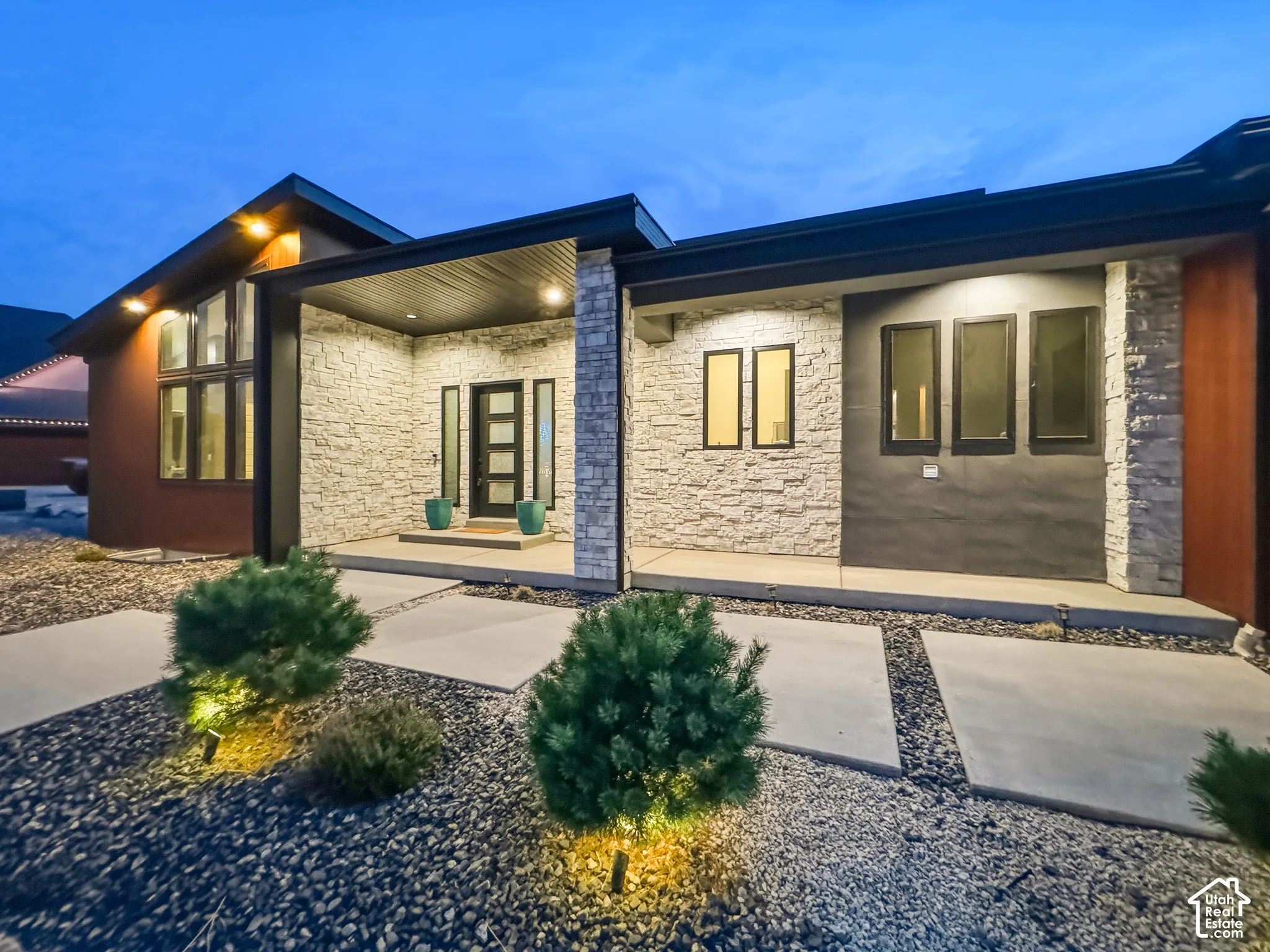 Modern exterior with a stone facade, a covered entry, and integrated exterior lighting