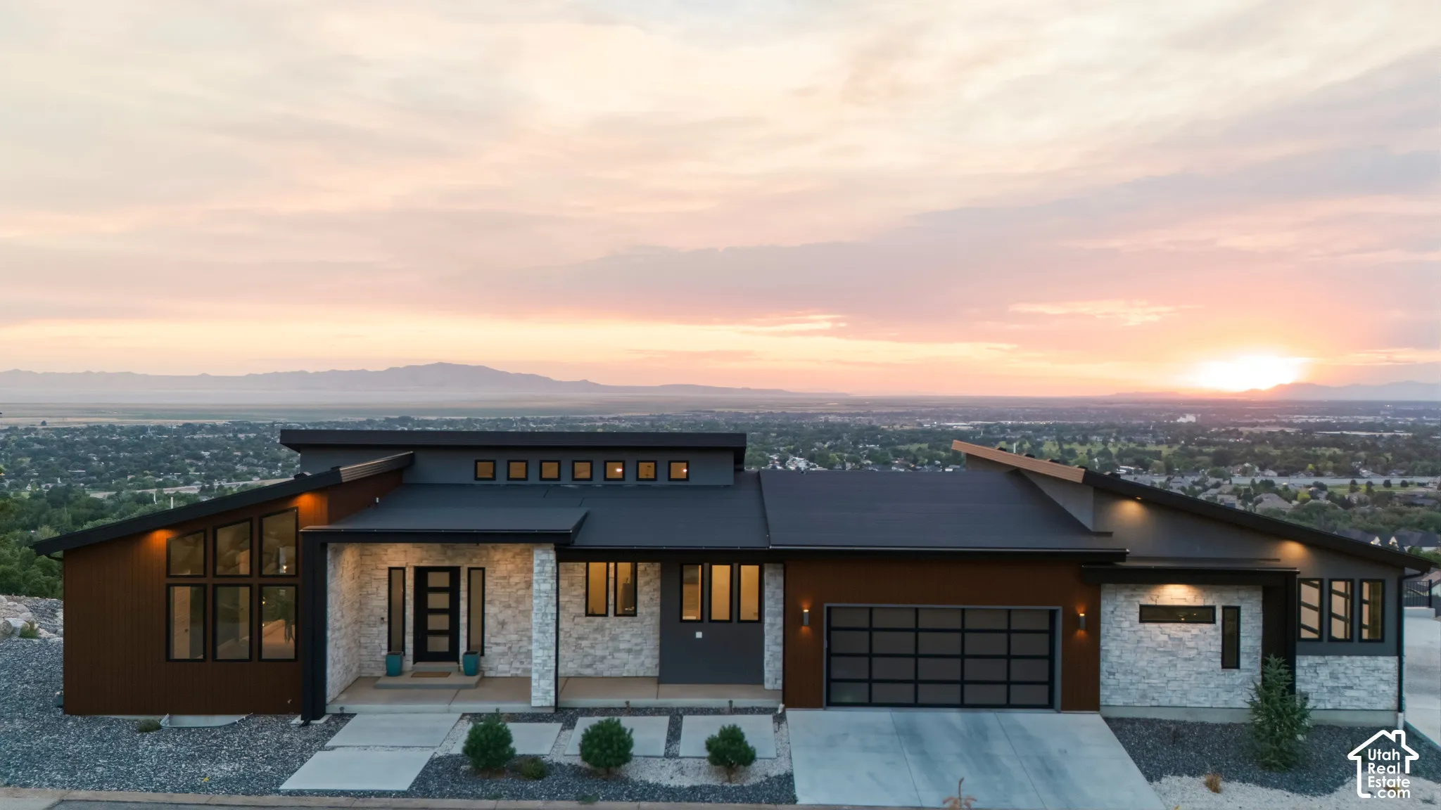 Modern architectural design with a sloped roofline, stone veneer accents, and dark wood-look siding