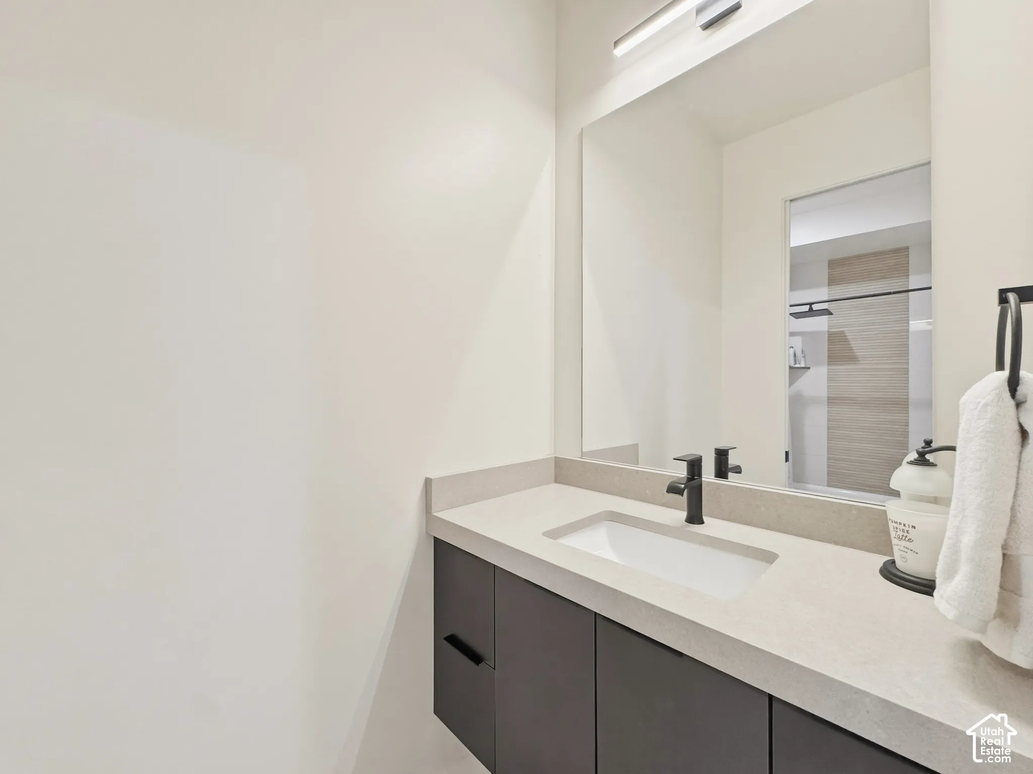 Floating vanity with a light-toned countertop, integrated sink, and matte black faucet