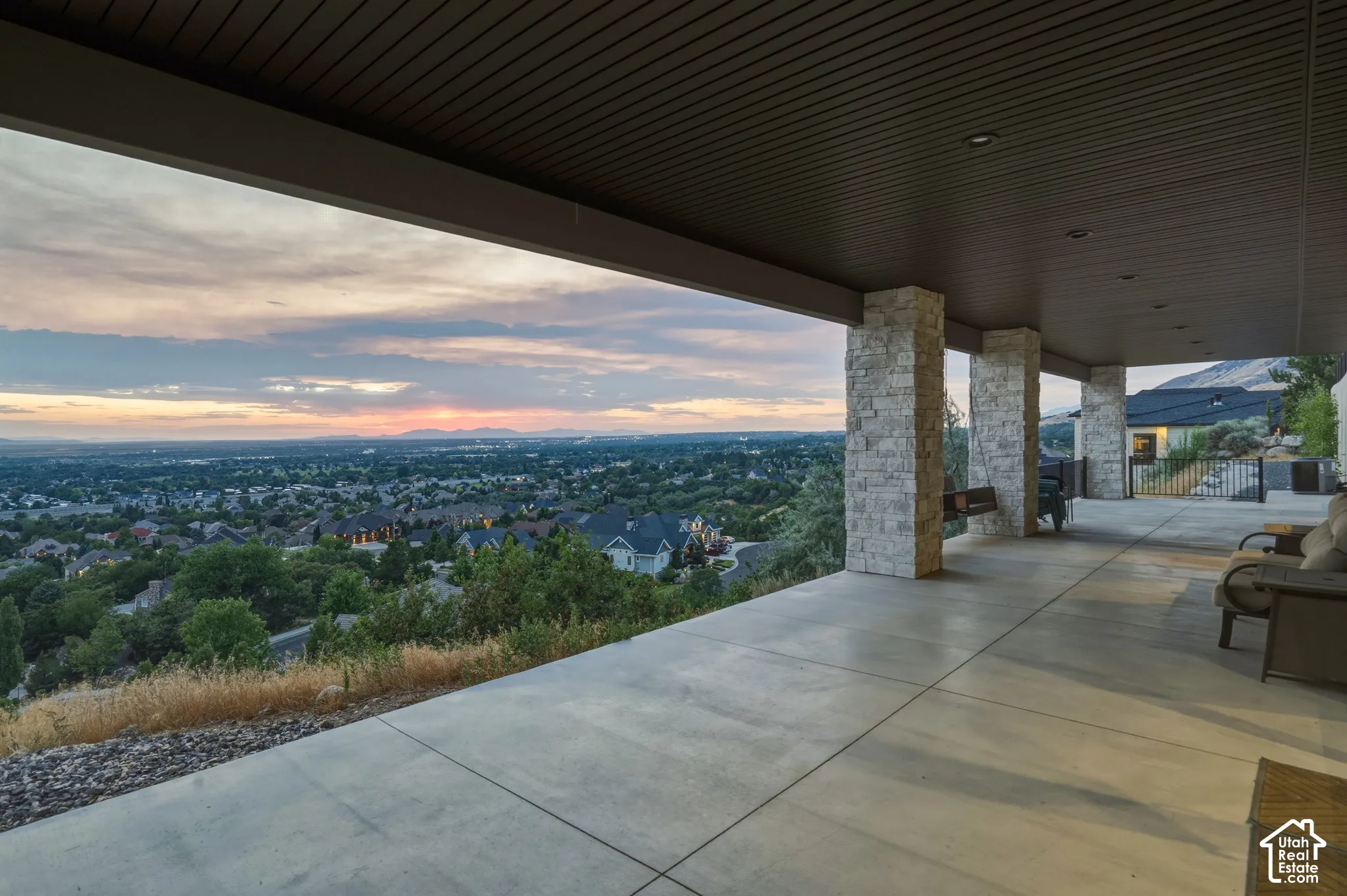 Expansive covered patio with stone-clad columns, recessed lighting, concrete flooring, and panoramic scenery