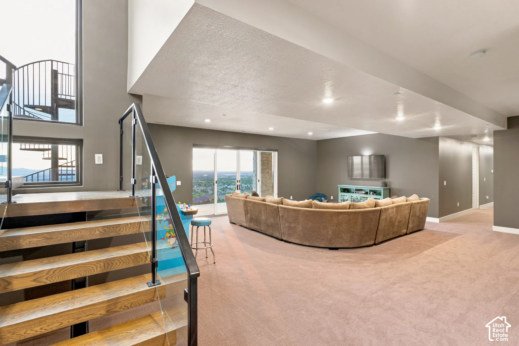 Hardwood stairs with glass and metal railing, recessed lighting, and sliding glass doors to outdoor space