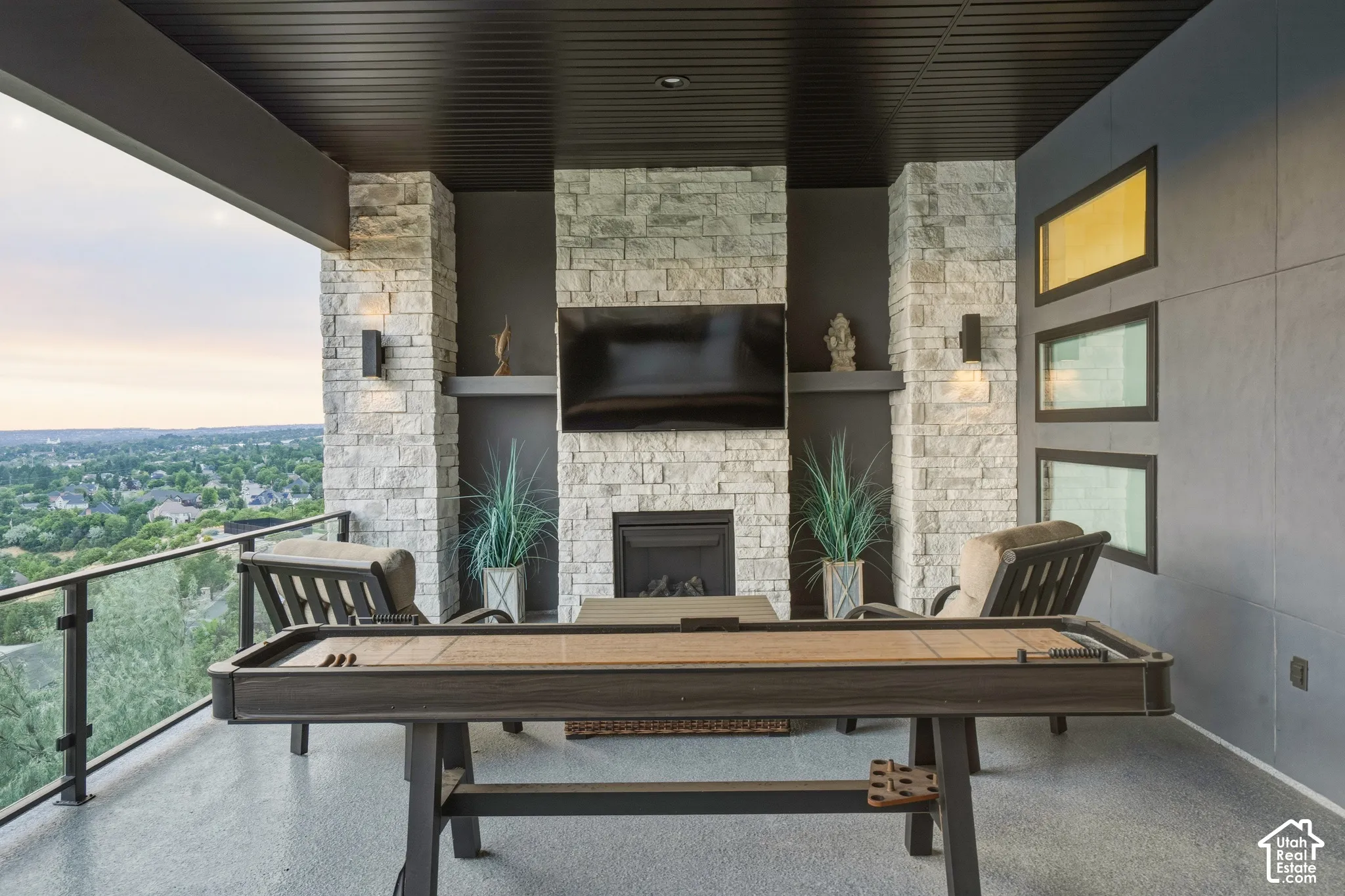 Expansive covered patio featuring a stone-clad fireplace and integrated television recess
