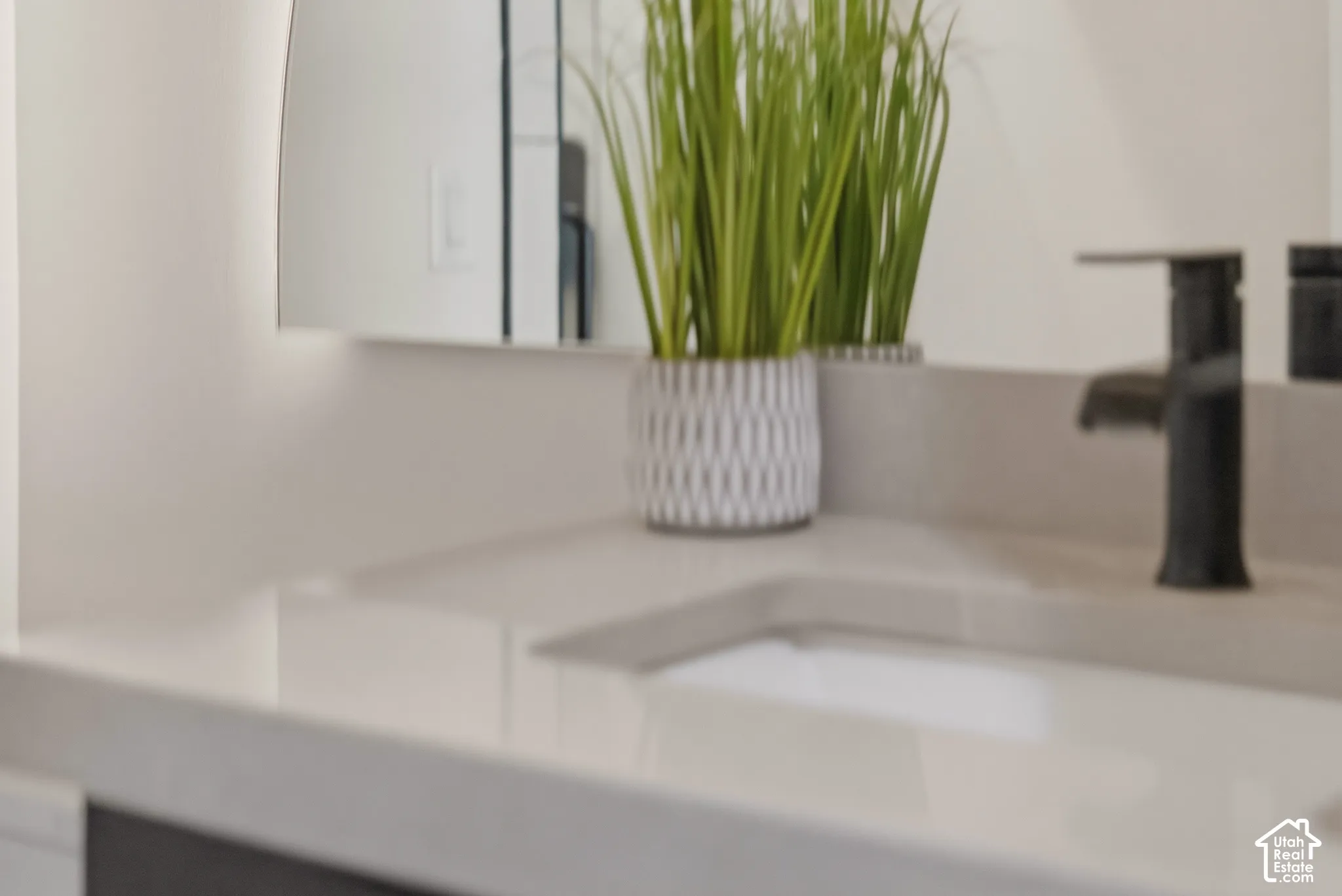 Integrated sink with matte black faucet, smooth countertop, and illuminated mirror