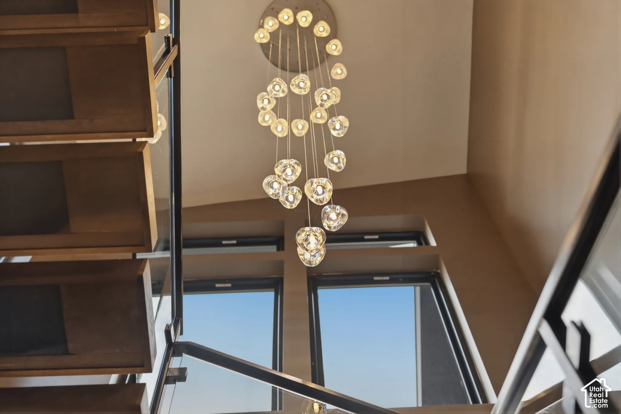 Contemporary chandelier with multiple pendant lights, wood-finish open risers, and glass panel railing