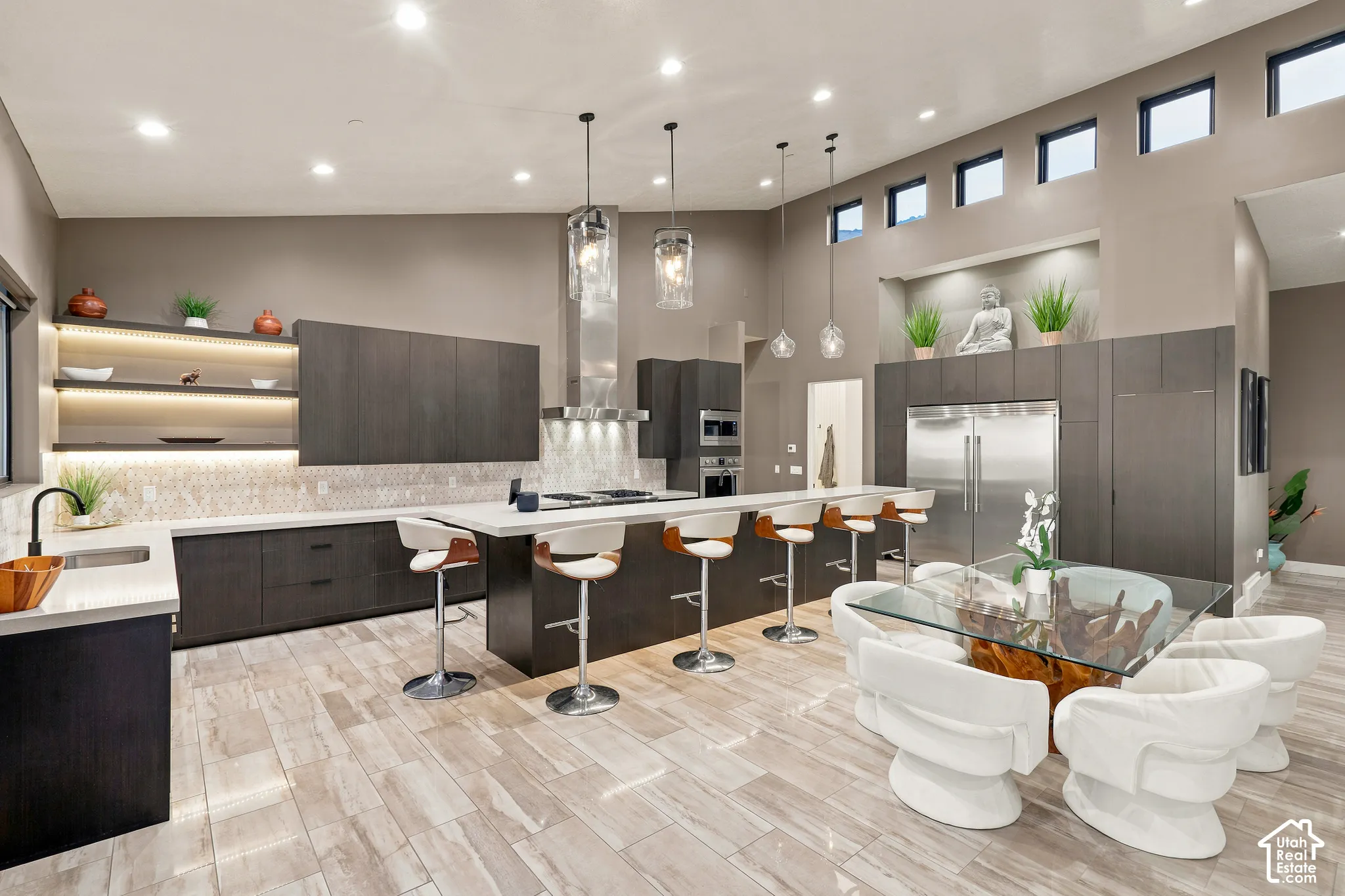 Expansive kitchen featuring a large central island, stainless steel appliances, custom cabinetry, and high ceilings with clerestory windows