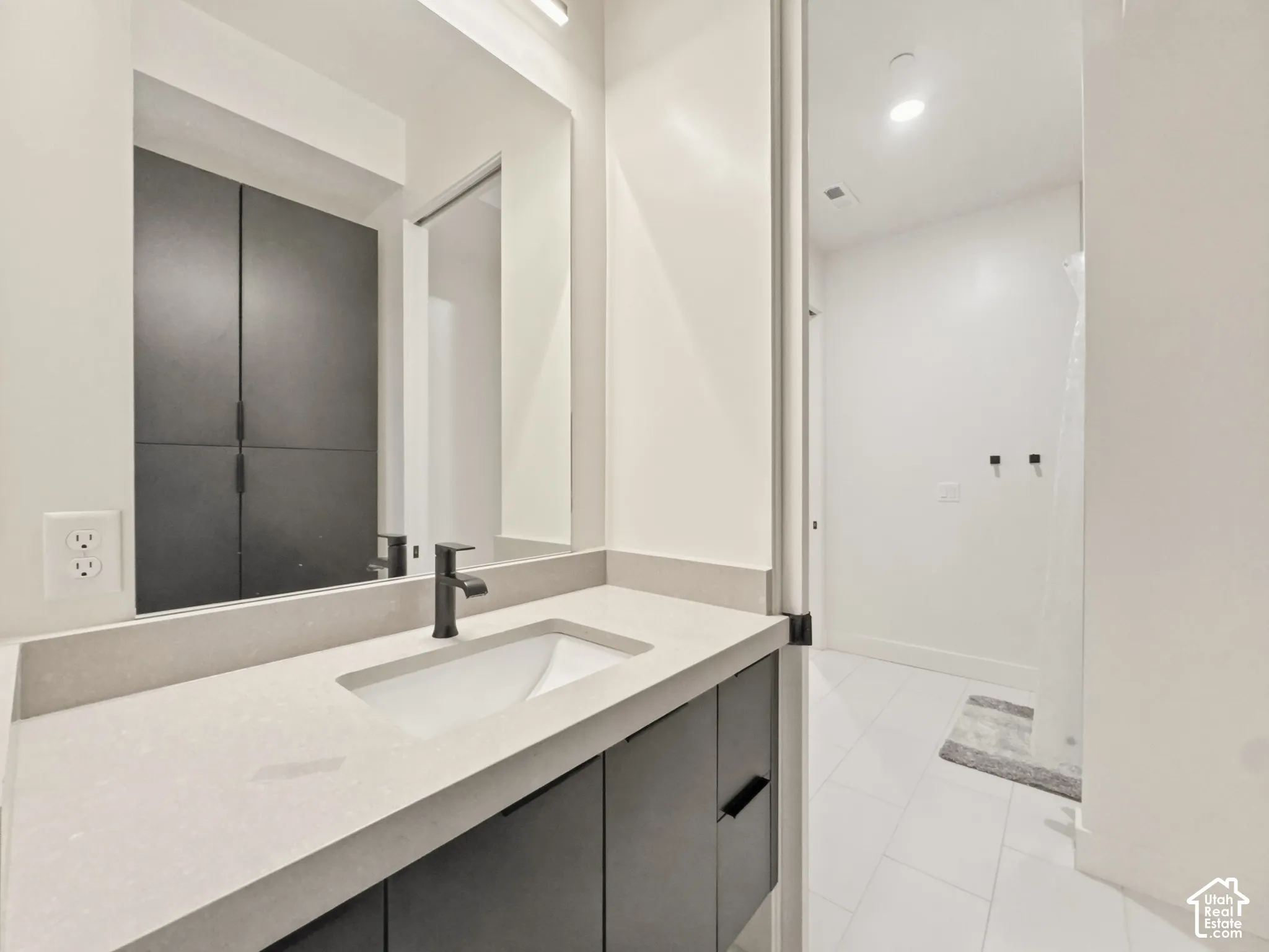 Vanity with integrated sink, matte black faucet, and light-colored countertop