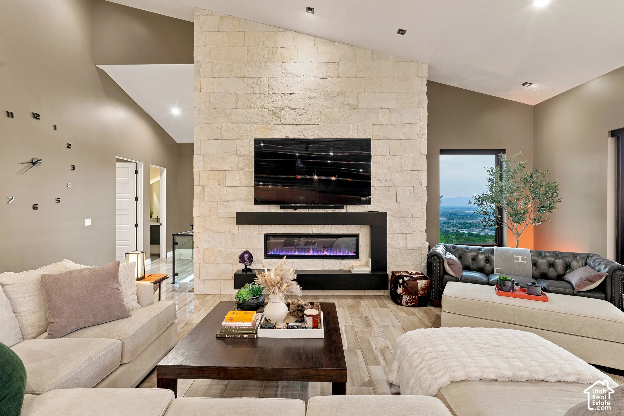 Vaulted ceilings, a stone-clad fireplace with an integrated electric insert, wood-finish flooring, and recessed lighting
