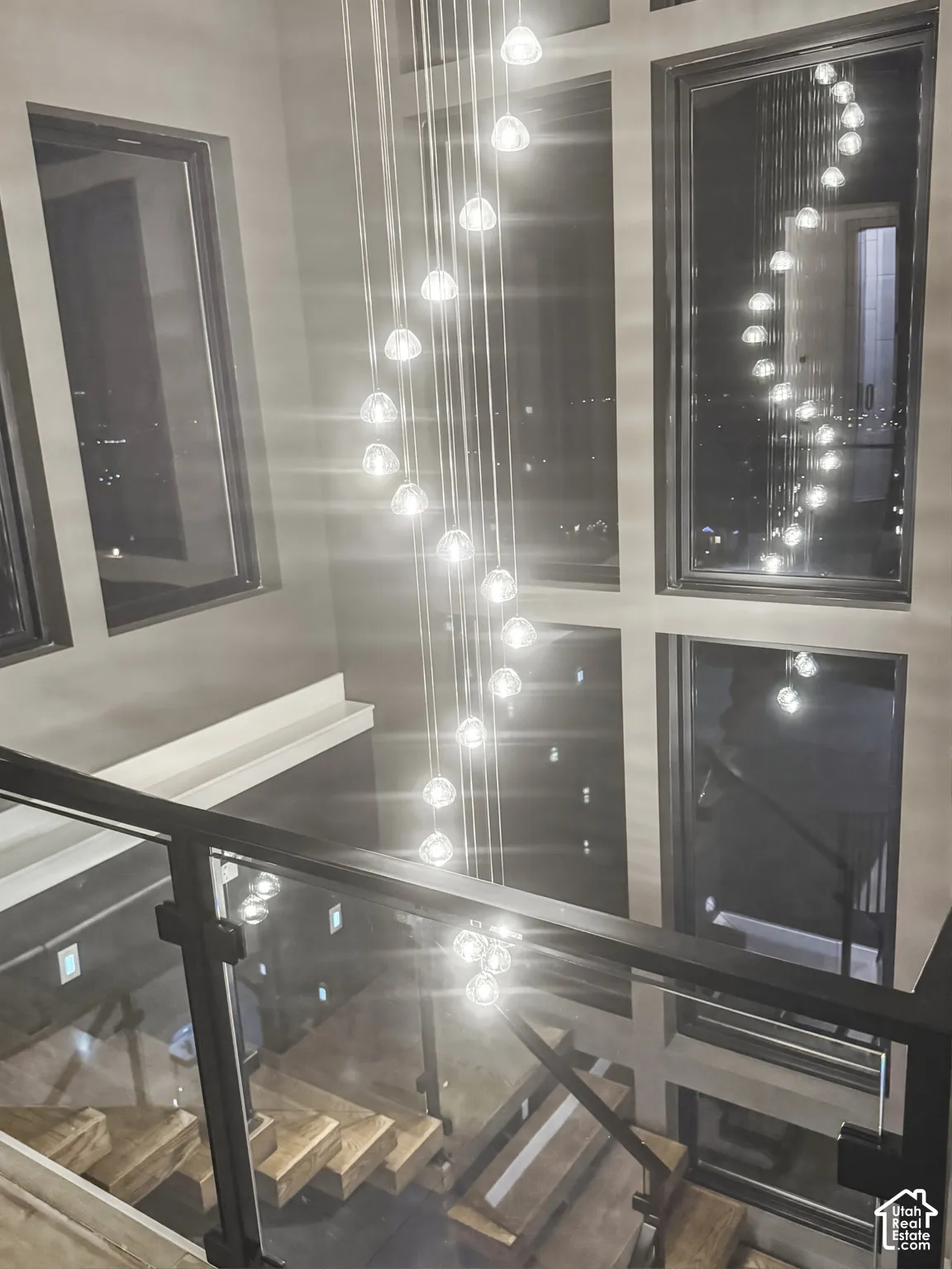 Grand staircase featuring wood-finish treads, glass railing panels, and a matte black handrail