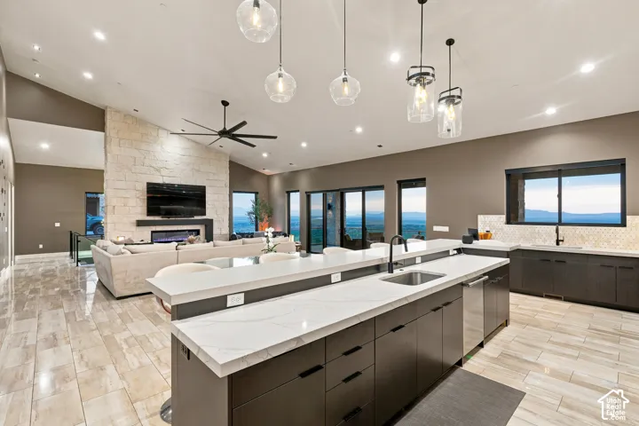 Open-concept living space featuring vaulted ceilings, a stone-clad fireplace, and expansive windows