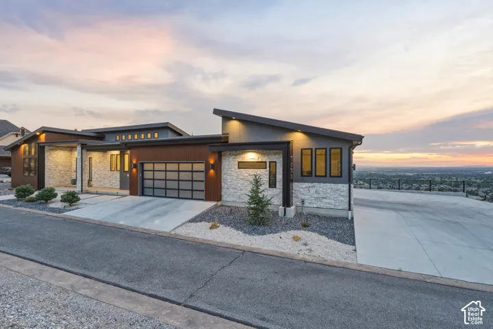 Modern architectural exterior featuring stone veneer, horizontal wood-finish siding, and a contemporary frosted-panel garage door