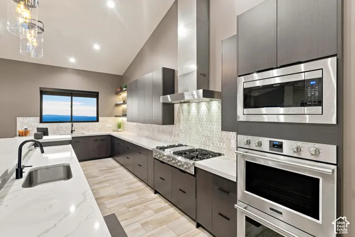 Contemporary kitchen featuring stainless steel appliances, white countertops, dark wood-finish cabinetry, and a patterned tile backsplash