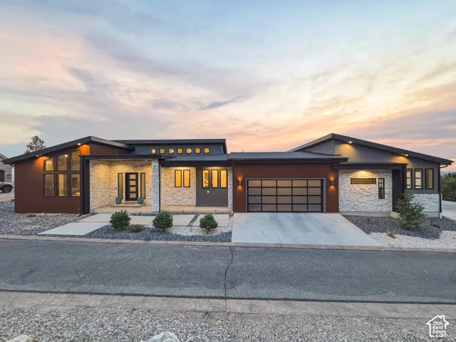 Contemporary exterior with a flat and pitched roofline, stone veneer accents, wood-finish siding, a sectioned garage door, and a concrete driveway