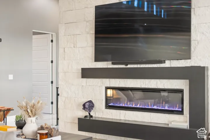Stacked stone fireplace with an integrated electric insert, mounted television, and floating shelving