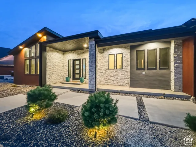 Modern exterior with a stone facade, a covered entry, and integrated exterior lighting