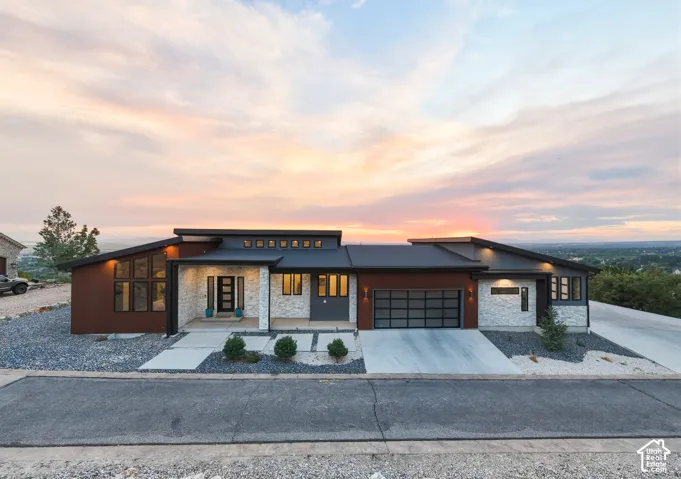 Contemporary exterior with a multi-textured facade, featuring extensive glazing, a prominent front entry, a two-car garage, and a concrete driveway