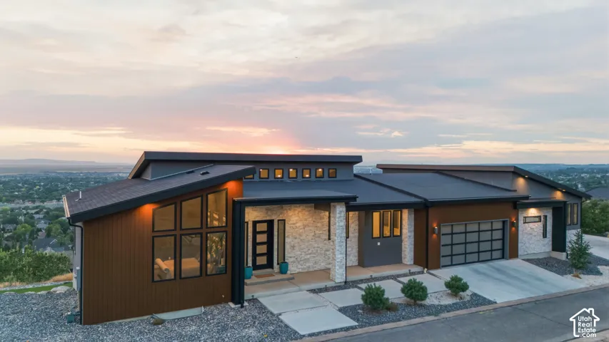 Modern architectural design with a multi-textured exterior, expansive window arrangements, a prominent two-car garage, and a concrete driveway
