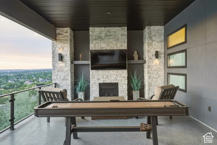 Expansive covered patio featuring a stone-clad fireplace and integrated television recess