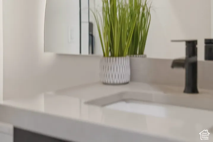 Integrated sink with matte black faucet, smooth countertop, and illuminated mirror