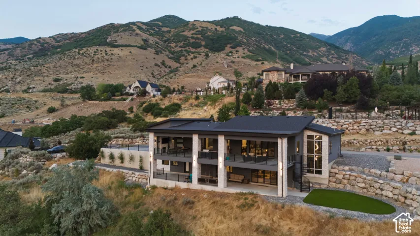 Modern multi-level exterior with a flat roof, stone accents, multiple balconies, and expansive glass doors