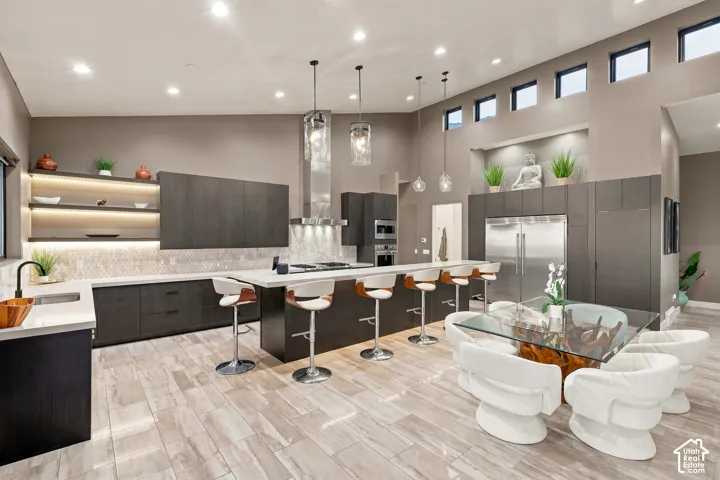 Expansive kitchen featuring a large central island, stainless steel appliances, custom cabinetry, and high ceilings with clerestory windows