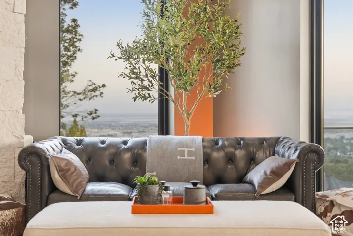 Expansive windows offering broad outdoor scenery, stone accent wall, and a refined seating area with a tufted sofa