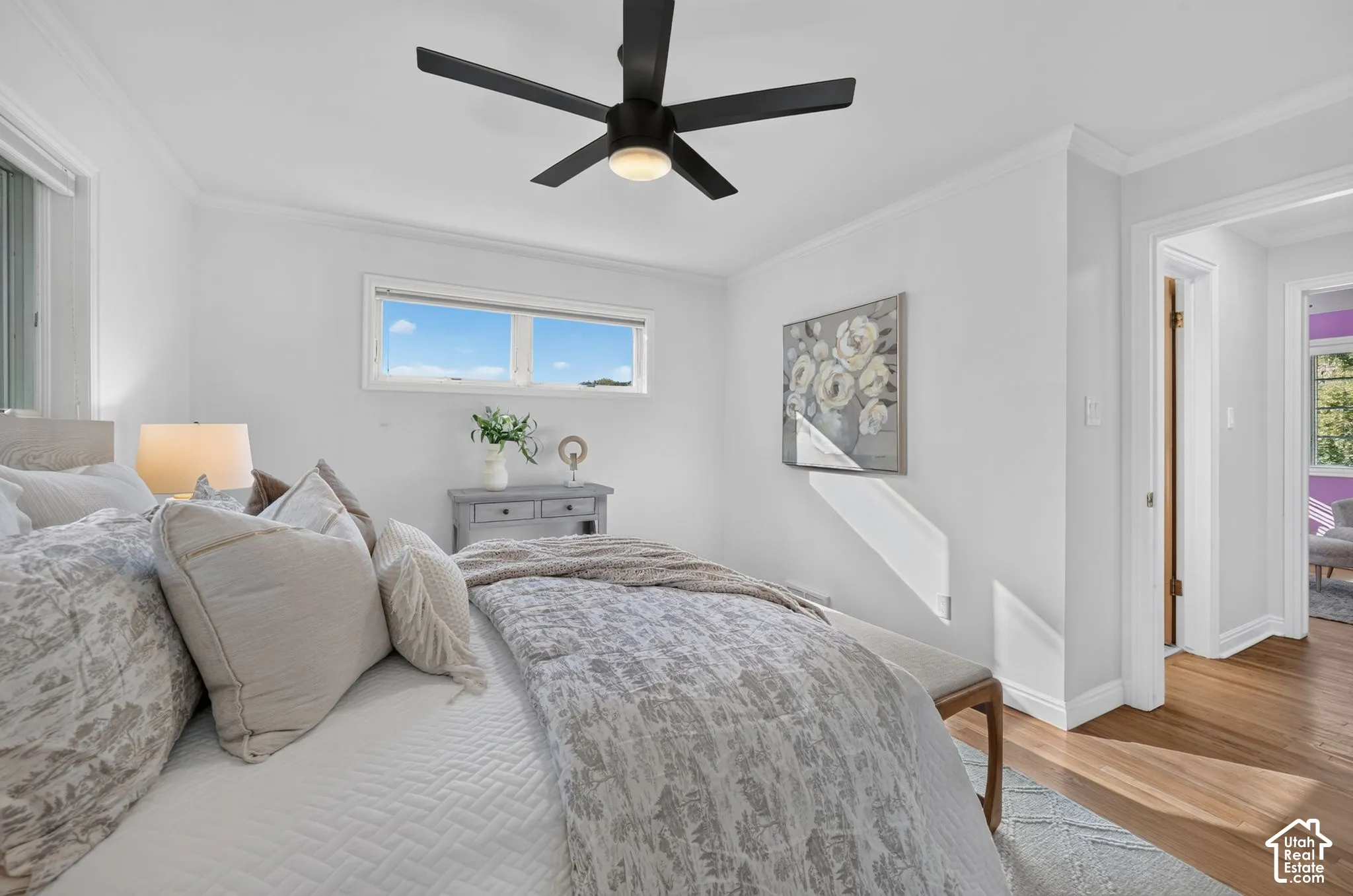 Primary bedroom with a ceiling fan and hardwood floors.