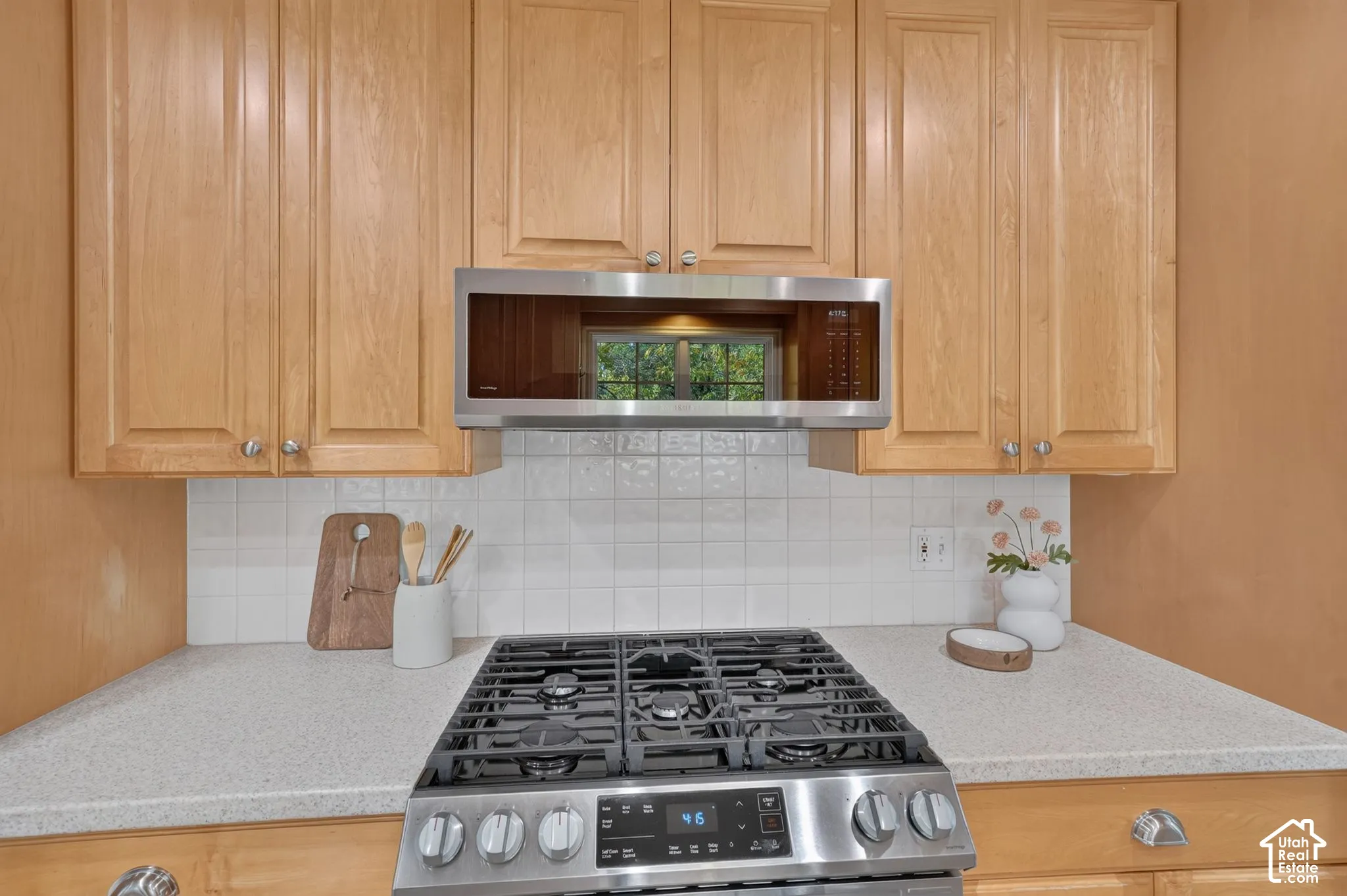Gas range with over-range microwave and white tile backsplash.