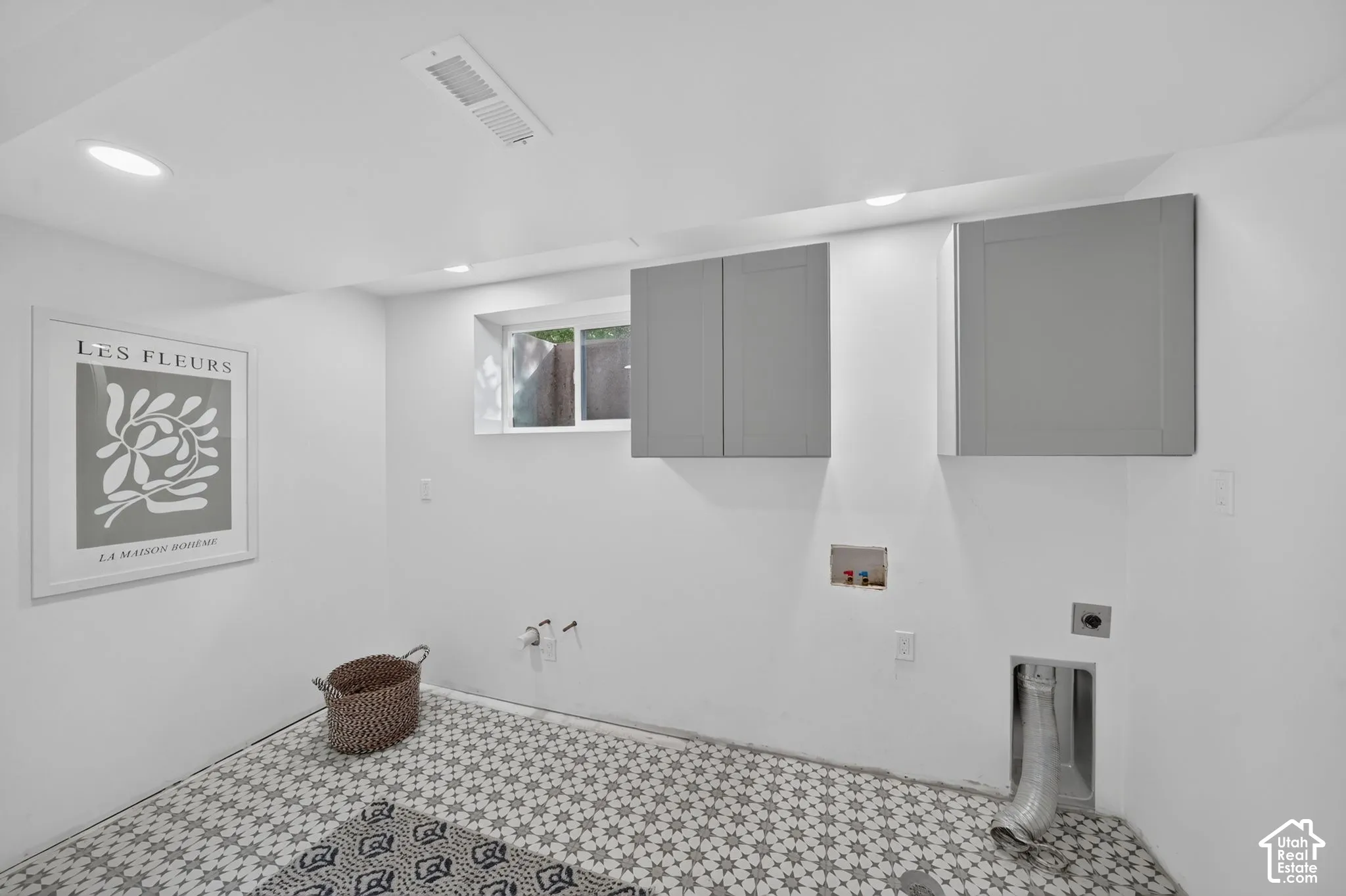 Laundry room with hookups, upper cabinets, and patterned tile floor.