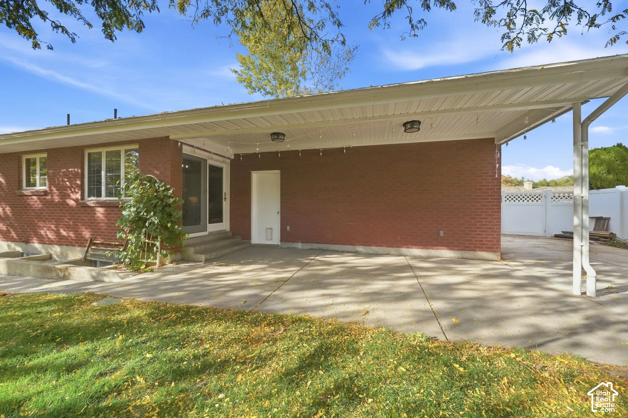 Back of the brick rambler with a covered patio and a glass door to the dining room.