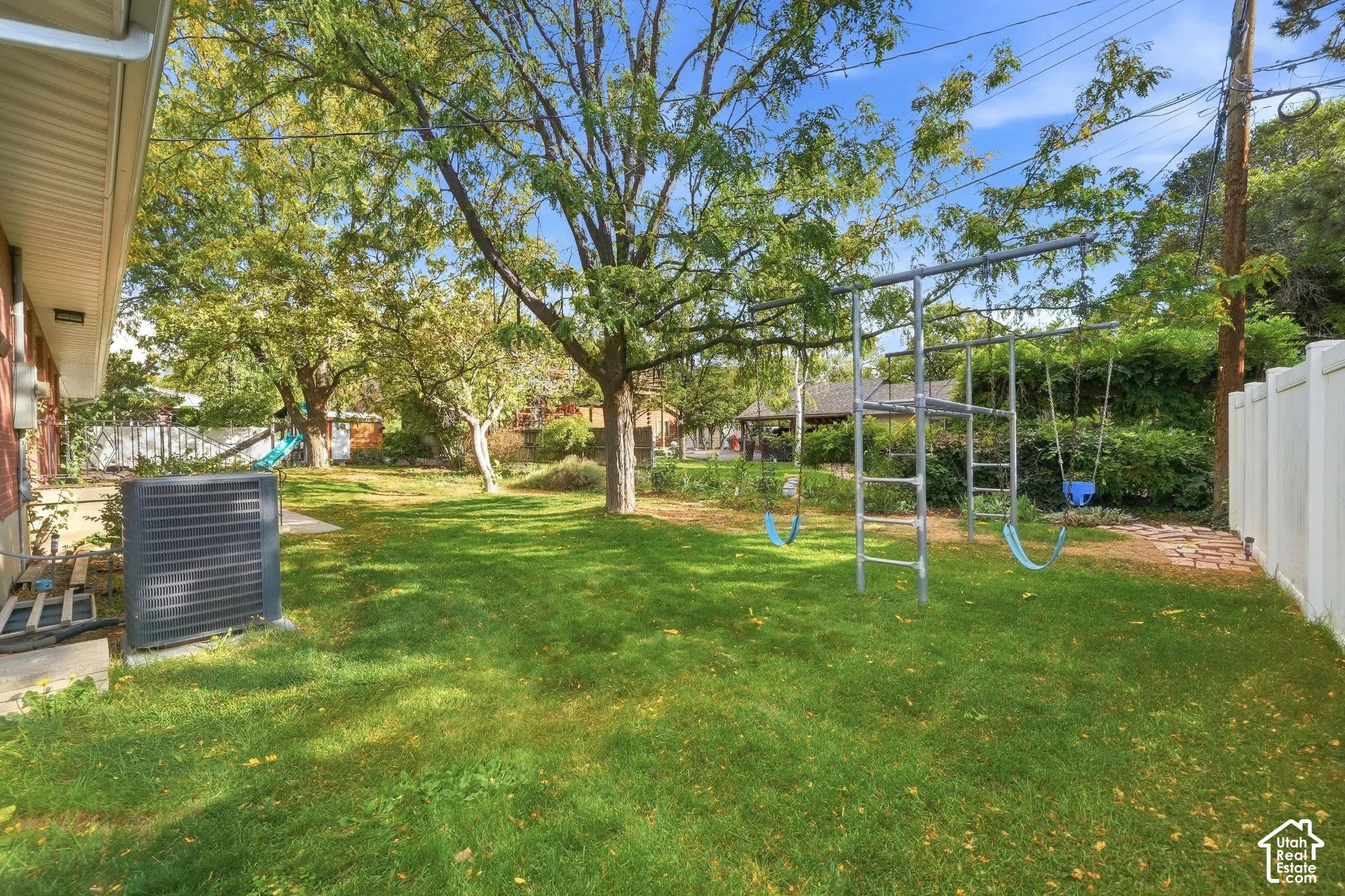Shady, fenced backyard with a built-in playground and mature trees.