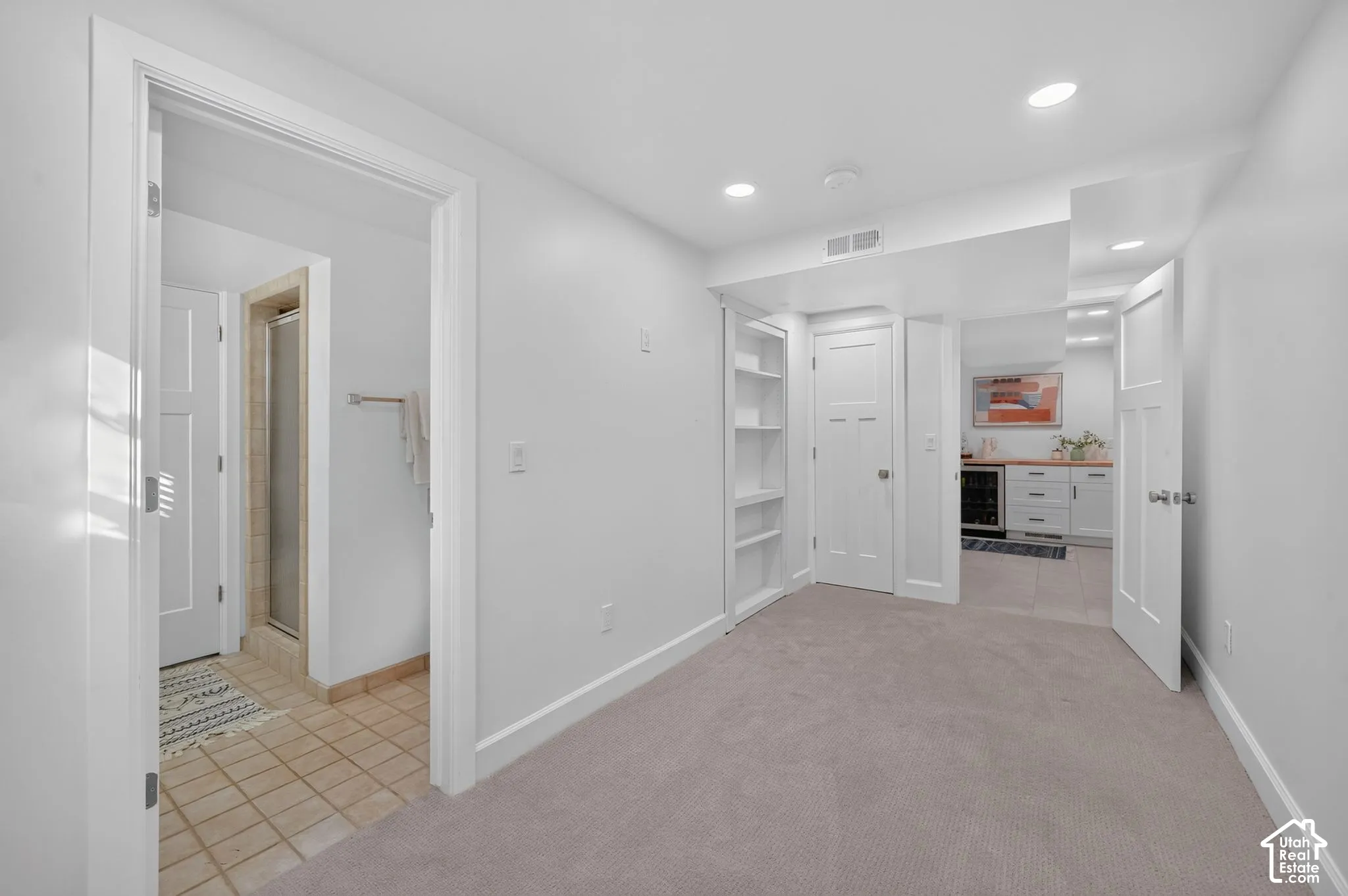 Lower-level bedroom (unstaged) with built-in shelving, an adjacent bath, and the wet-bar area beyond.