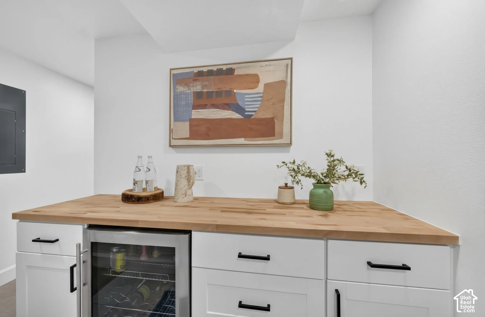 Wet bar with a butcher-block counter, cabinetry, and a beverage/wine fridge.