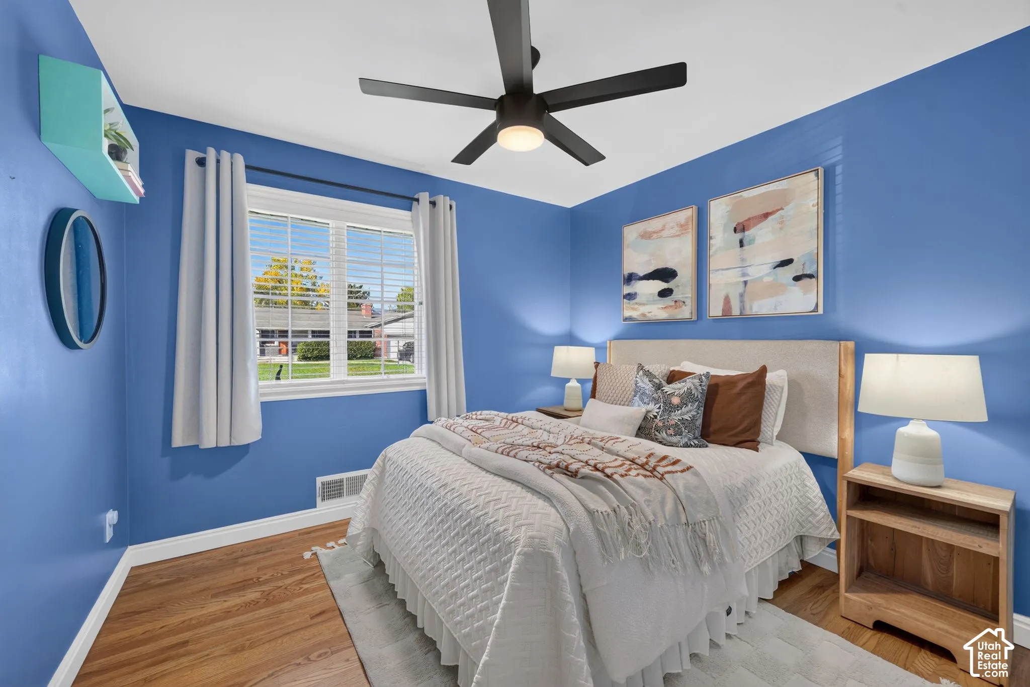 Main-floor bedroom with hardwood floors and a ceiling fan.