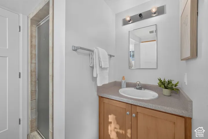 Lower-level three-quarter bath with a tiled shower and wood vanity.
