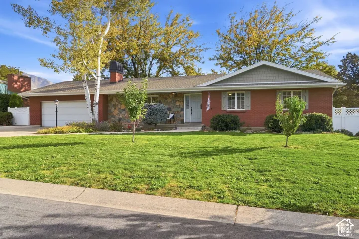 1959 brick rambler with stone accents, mature trees, and a level front lawn on a quiet Millcreek street.