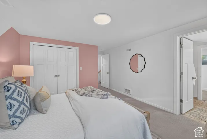 The same lower bedroom from the other side, with a double closet and a pink accent wall.
