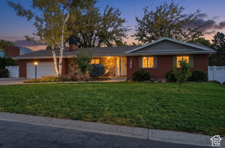 Brick-and-stone rambler with a covered front porch at dusk.