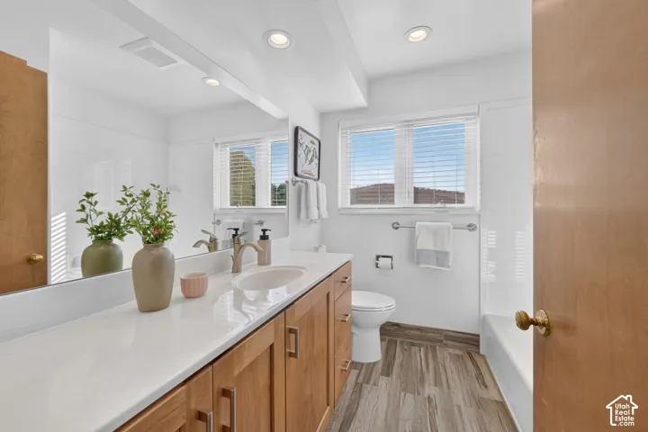 Second full bath with a tub, wood vanity, and wood-look tile floor.