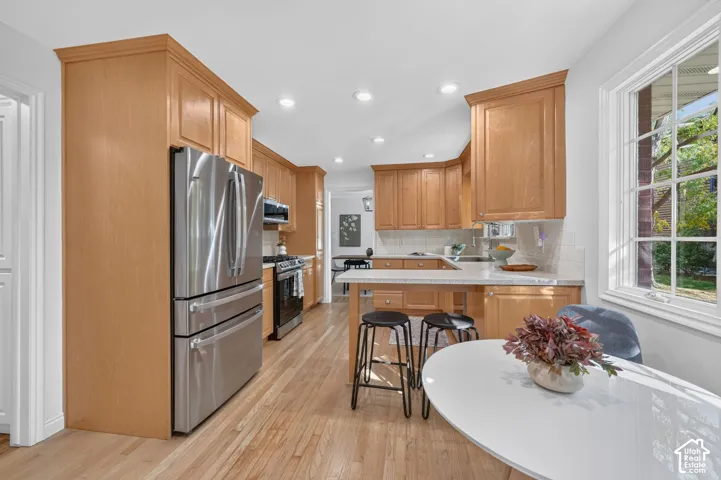 Updated kitchen with wood cabinets, stainless appliances, and bar seating.