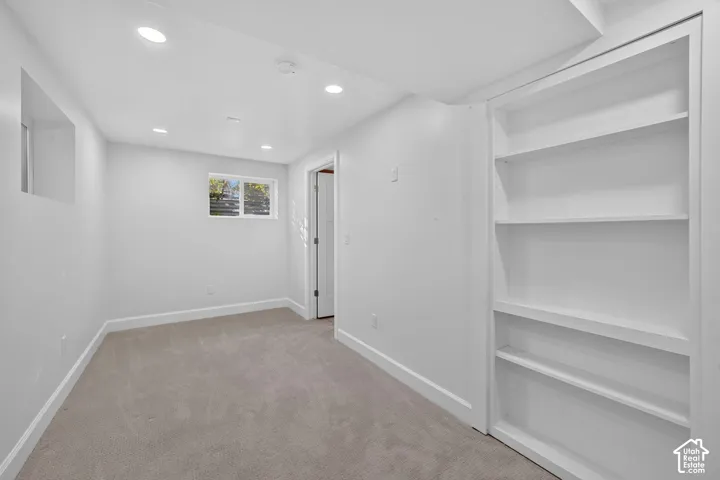 The same lower-level bedroom, with an egress window and built-in shelving.