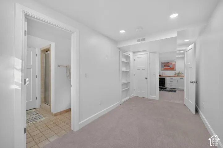 Lower-level bedroom (unstaged) with built-in shelving, an adjacent bath, and the wet-bar area beyond.