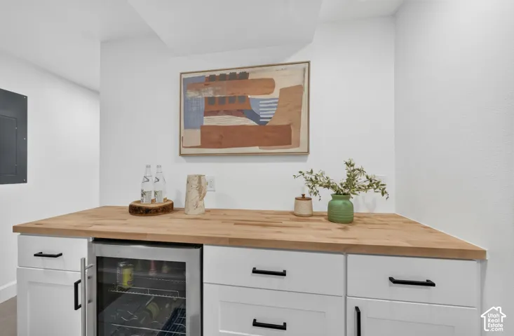 Wet bar with a butcher-block counter, cabinetry, and a beverage/wine fridge.
