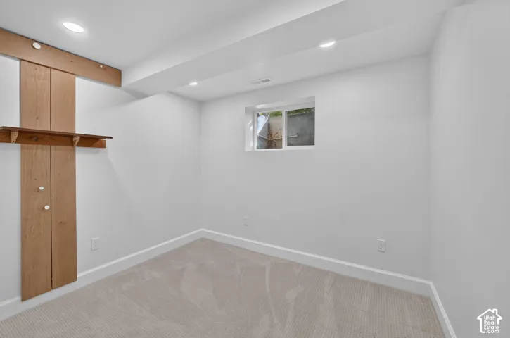 Lower-level bedroom with a built-in wood shelf and an egress window.