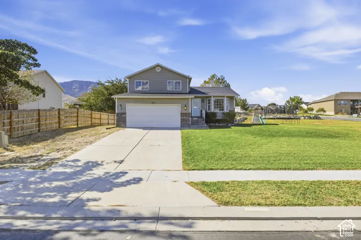 Two-story property with an attached two-car garage, partial stone facade, and a large front yard