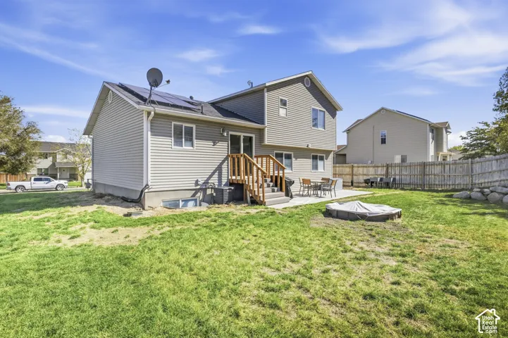 Expansive lawn with a concrete patio, wood-finish deck, and privacy fencing