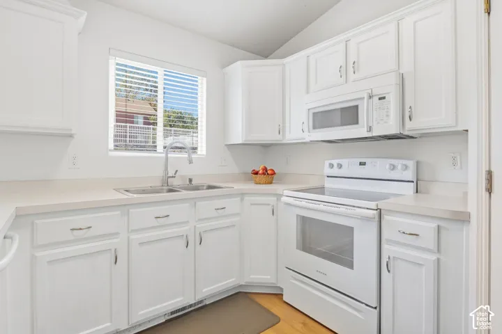 White kitchen cabinetry with brushed nickel hardware, white countertops, built-in microwave, and electric range